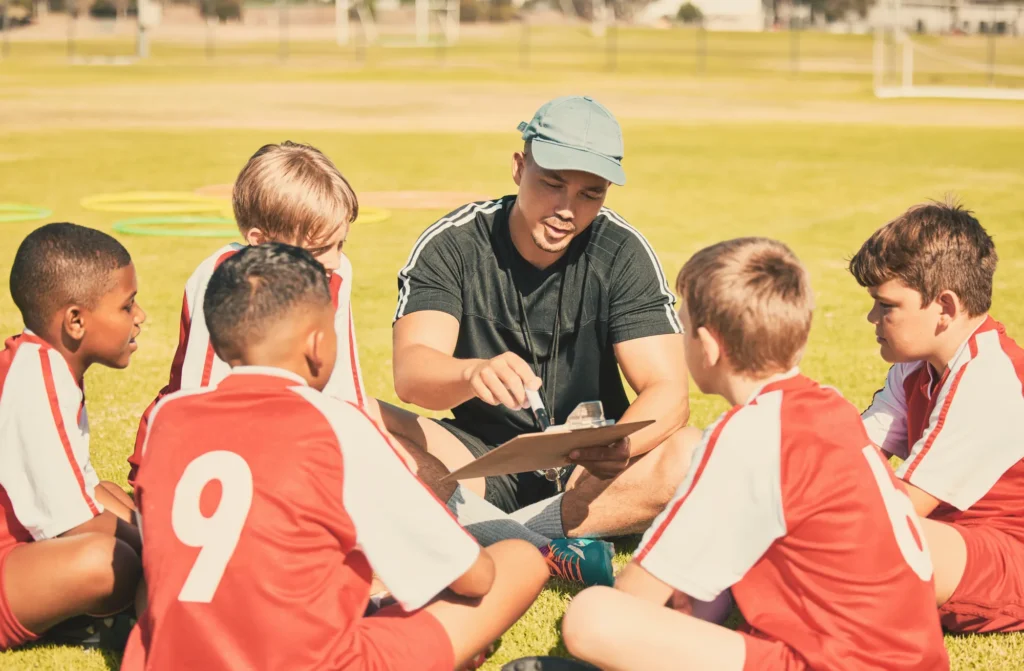 Treinador conversa com a turma de futebol no campo